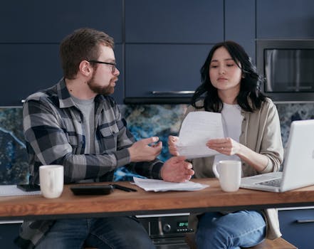 A couple reviews financial documents together at home, focusing on budgeting and bills.