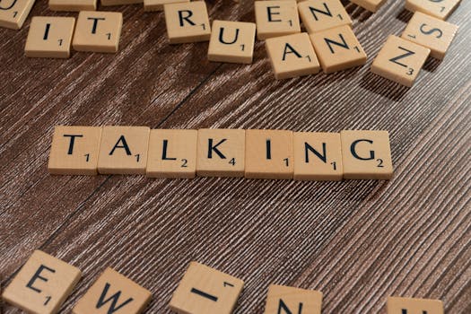 Scrabble tiles spelling 'Talking' on wooden surface, symbolizing communication.