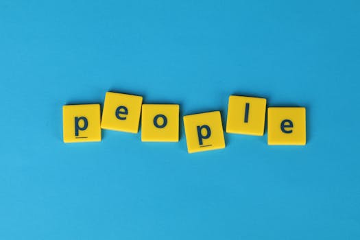 Yellow Scrabble tiles spelling 'people' on a blue background, vibrant and playful.