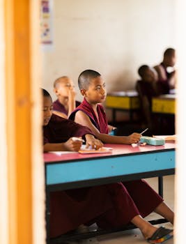 Young monks in a classroom setting, focused on learning in traditional robes.