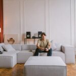 A young man sits on a modern sofa playing video games in a stylish living room interior.