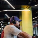 Adult man wearing headphones and exercising indoors, focused on fitness goals.
