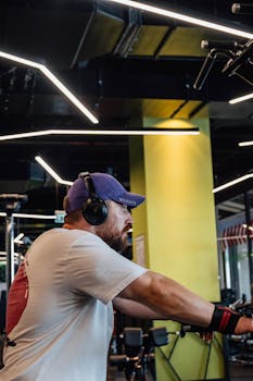 Adult man wearing headphones and exercising indoors, focused on fitness goals.
