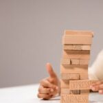 Close-up of a Jenga-like game with blocks labeled with emotions like 'Kindness' and 'Greed'.
