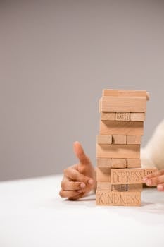 Close-up of a Jenga-like game with blocks labeled with emotions like 'Kindness' and 'Greed'.