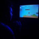 Man playing Super Mario Bros on TV, capturing retro gaming nostalgia.