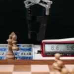 Robotic arm moves chess pieces on a board with electronic digital timer displayed.