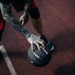 Tattooed player dribbling basketball on outdoor court. Dynamic and energetic capture.