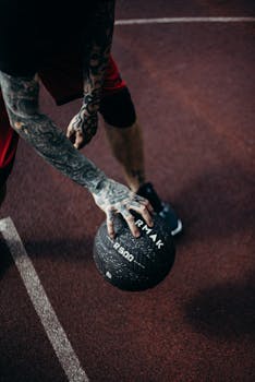 Tattooed player dribbling basketball on outdoor court. Dynamic and energetic capture.