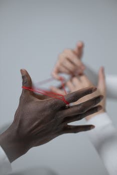 Two hands engage in a classic string game, focusing on connection.