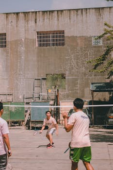 Two teenagers playing an outdoor badminton game with energy and focus.