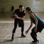 Two women playing basketball indoors, emphasizing competition and athleticism.